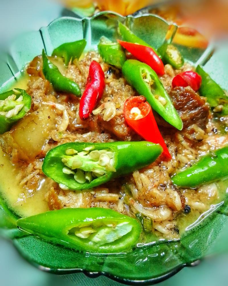 Pork in a coconut milk sauce with green and red chilies, in a green glass bowl