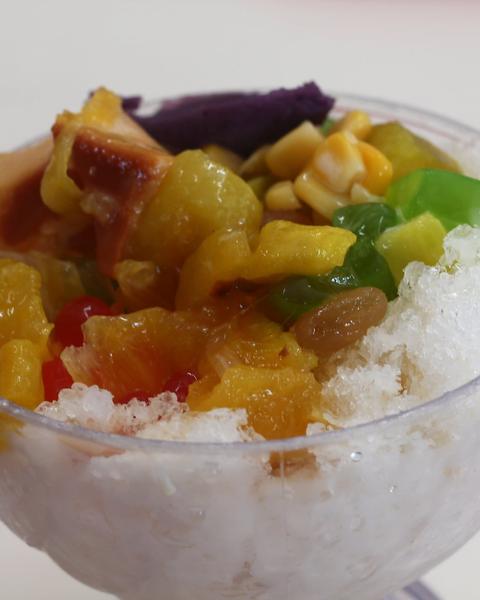 Shaved ice in a glass bowl with ube, jackfruit, corn and green jelly