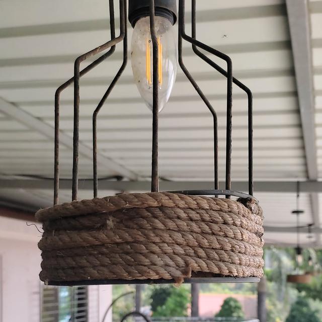 A rope-wrapped pendant light above a long counter beside an open terrace