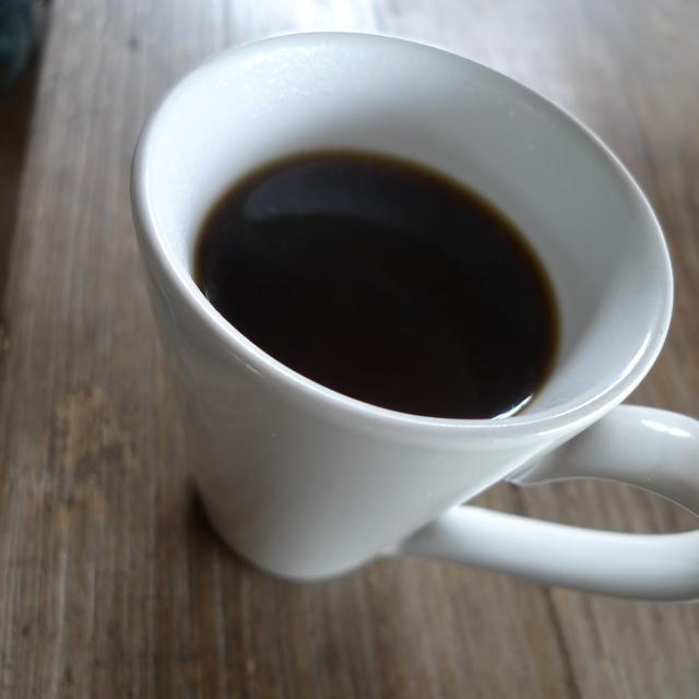 A white cup of black coffee seen from above on a wooden table