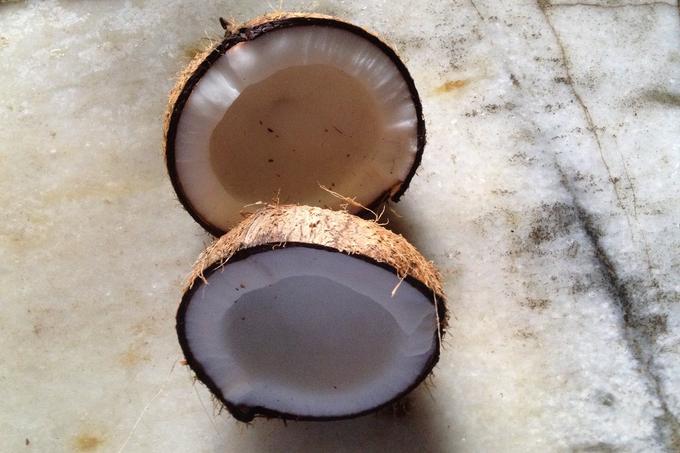 Two coconut halves on a pale stone surface