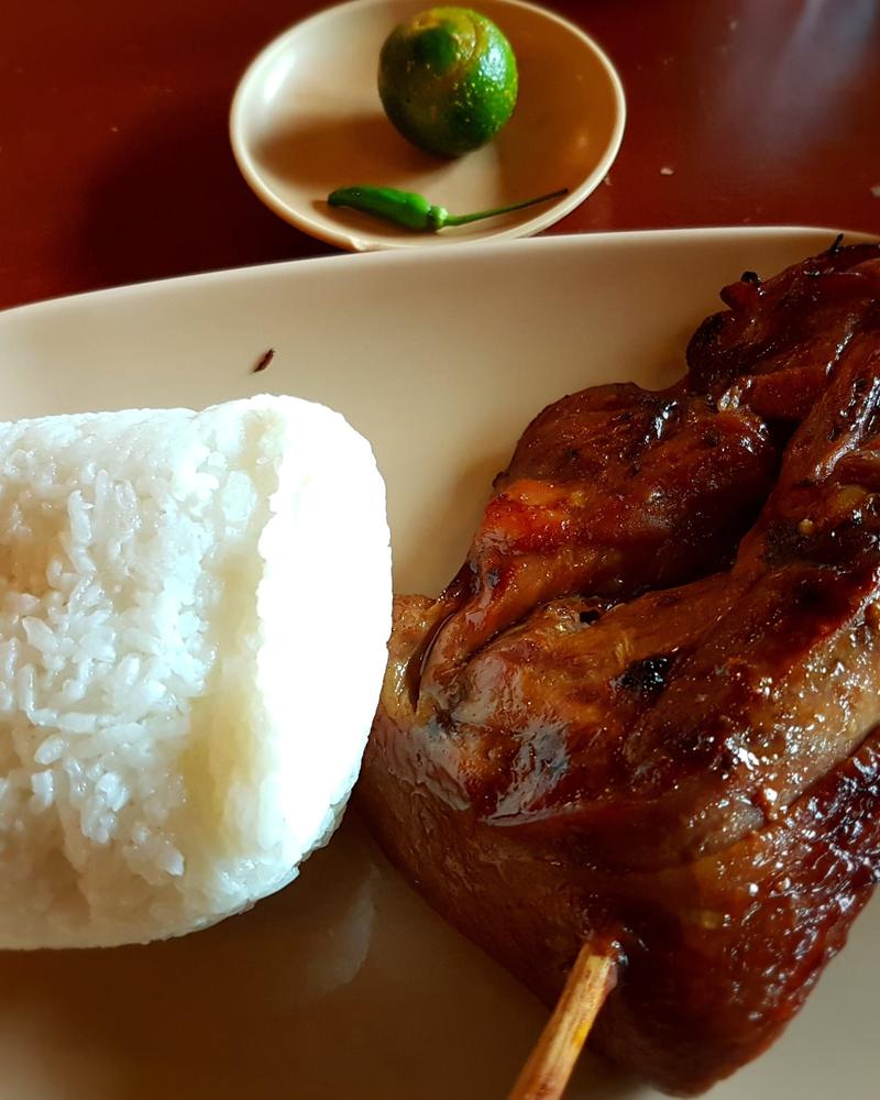 Grilled chicken inasal with a mound of white rice on a plate